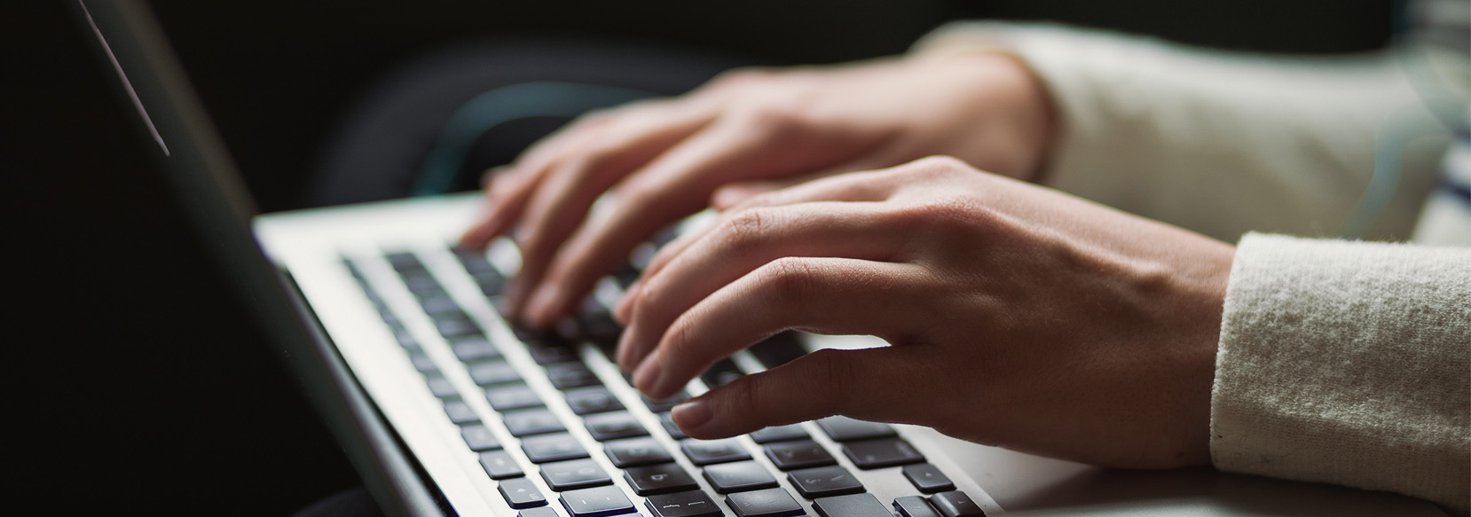 Hands typing on a laptop keyboard.
