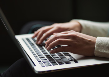 Hands typing on a laptop keyboard.