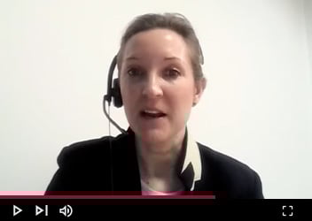 Video frame of a person with blond hair speaking, displayed on a video player interface.