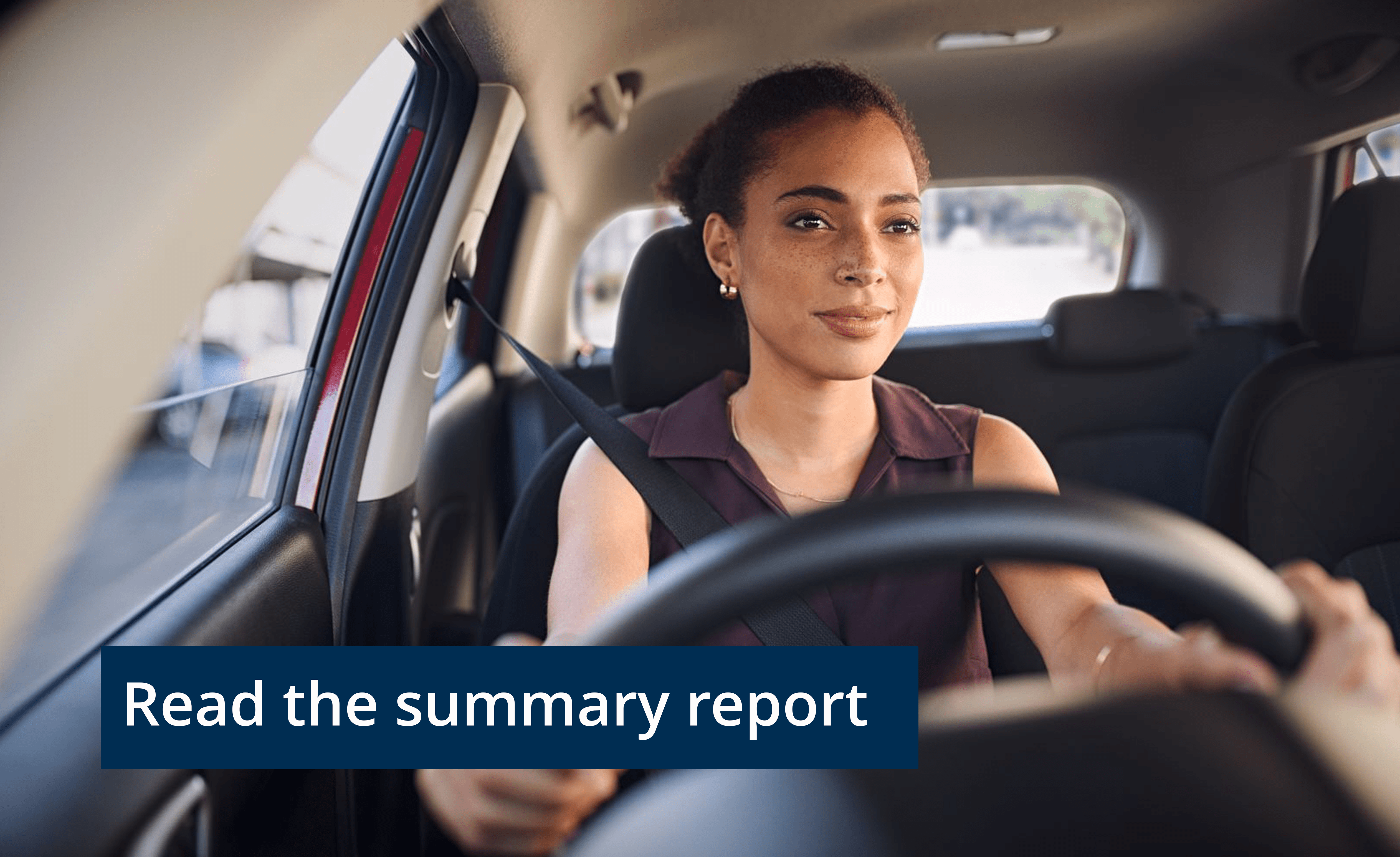 Close up of young woman driving a car and a banner at the bottom saying 'Read the summary report'.