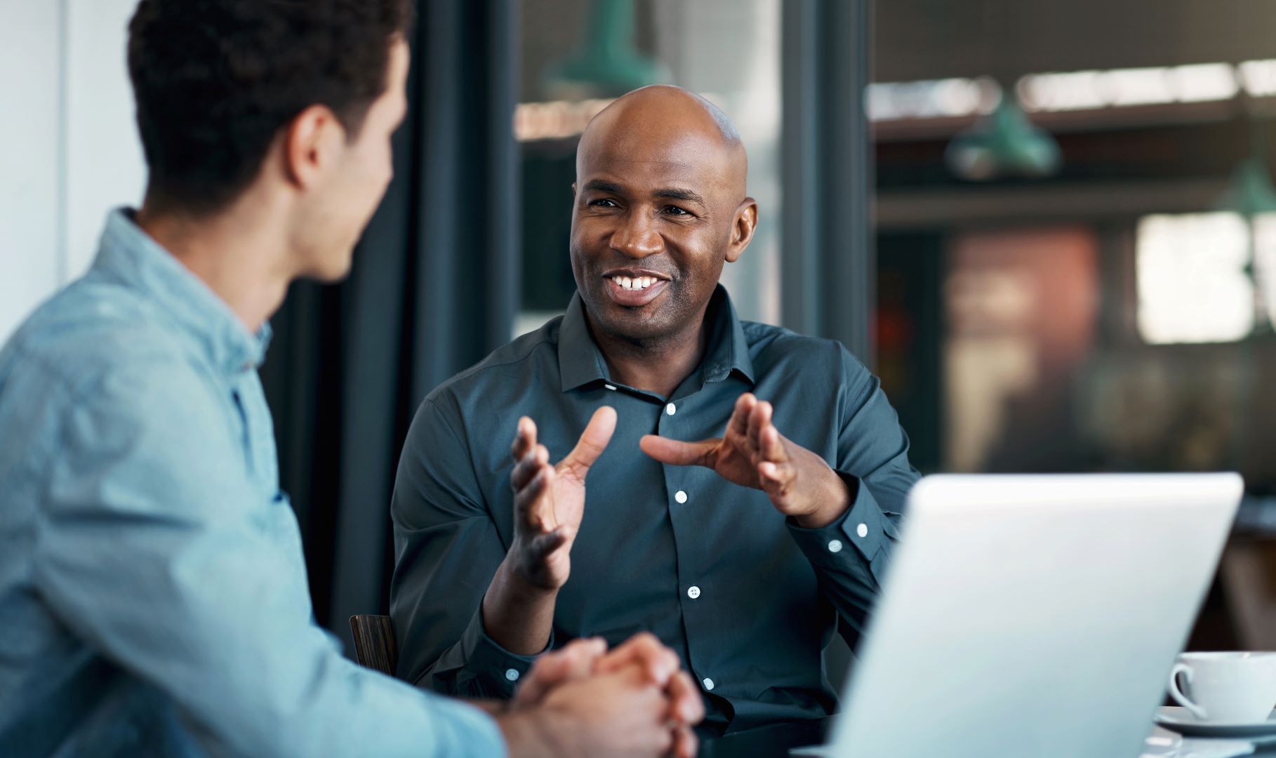 Two men talking sat beside a laptop